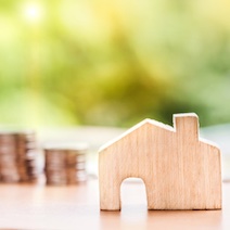 House with stacks of coins behind.